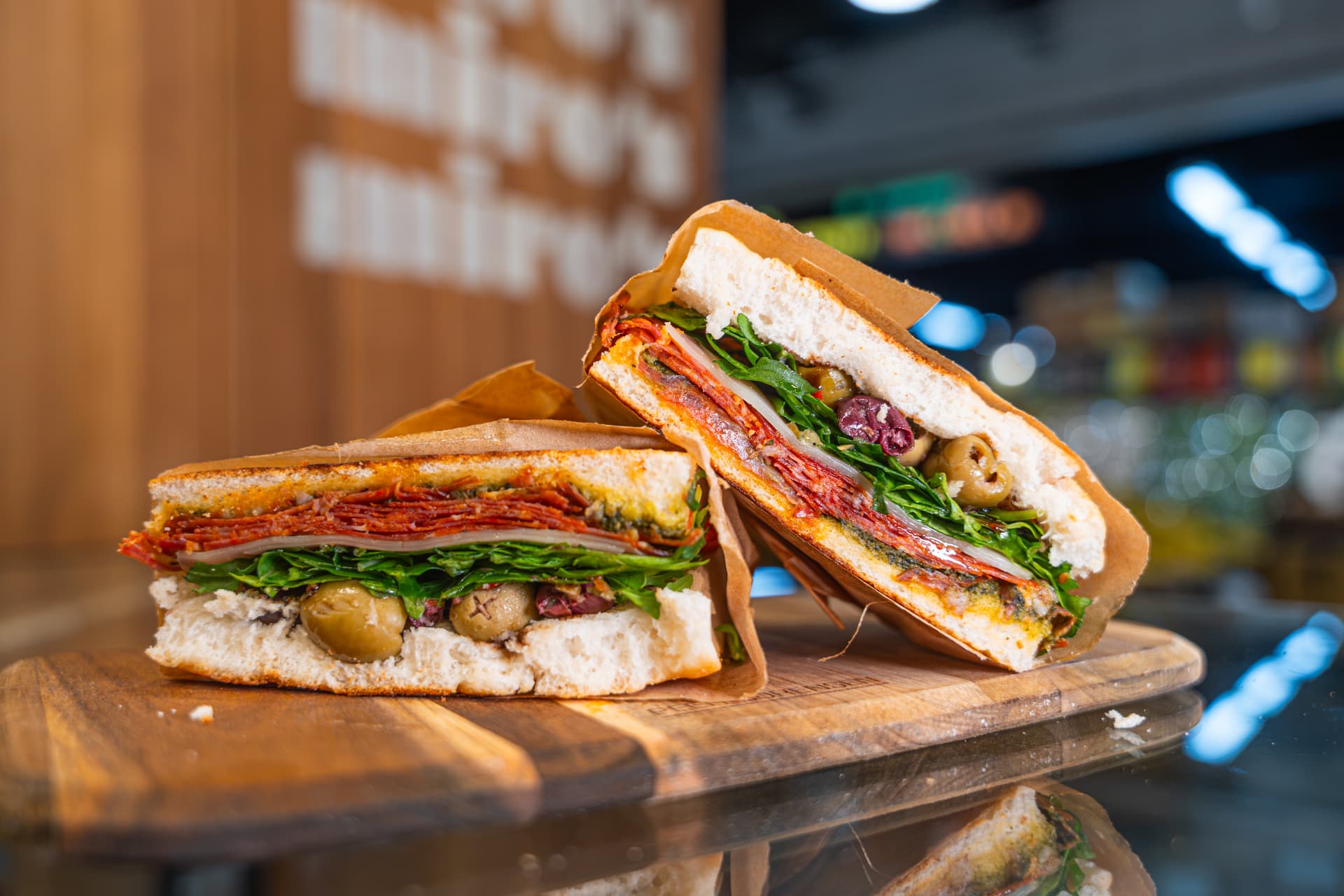 A freshly made Miro's Deli sandwich stacked on a wooden board